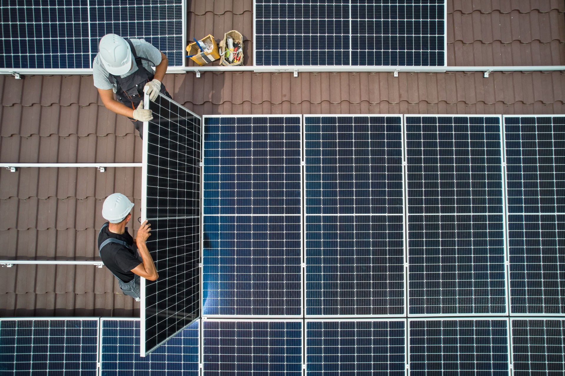 Men technicians mounting photovoltaic solar moduls on roof of house.