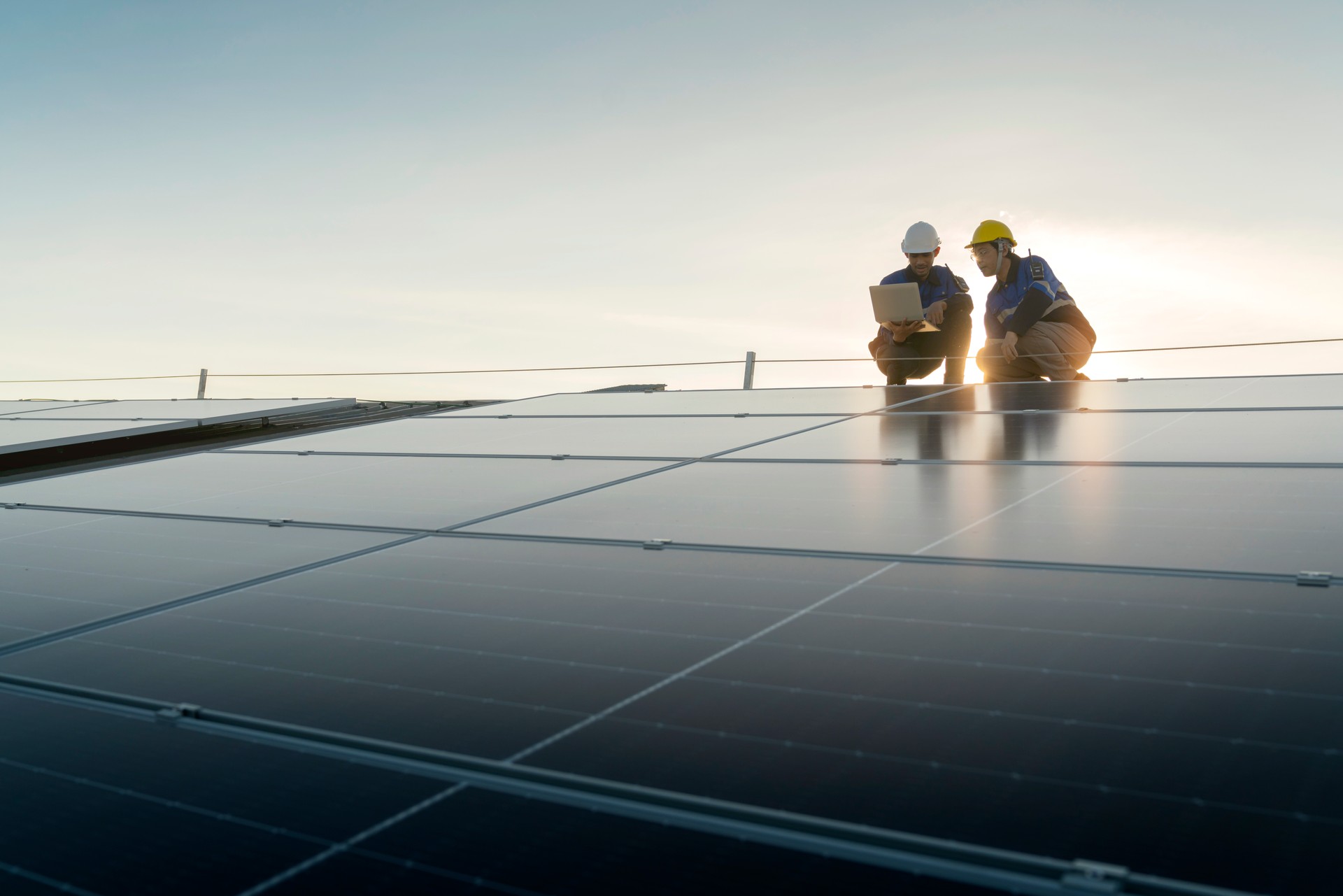 Specialist technician professional engineer with laptop and tablet maintenance checking installing solar roof panel on the factory rooftop under sunlight. Engineers team survey check solar panel roof.